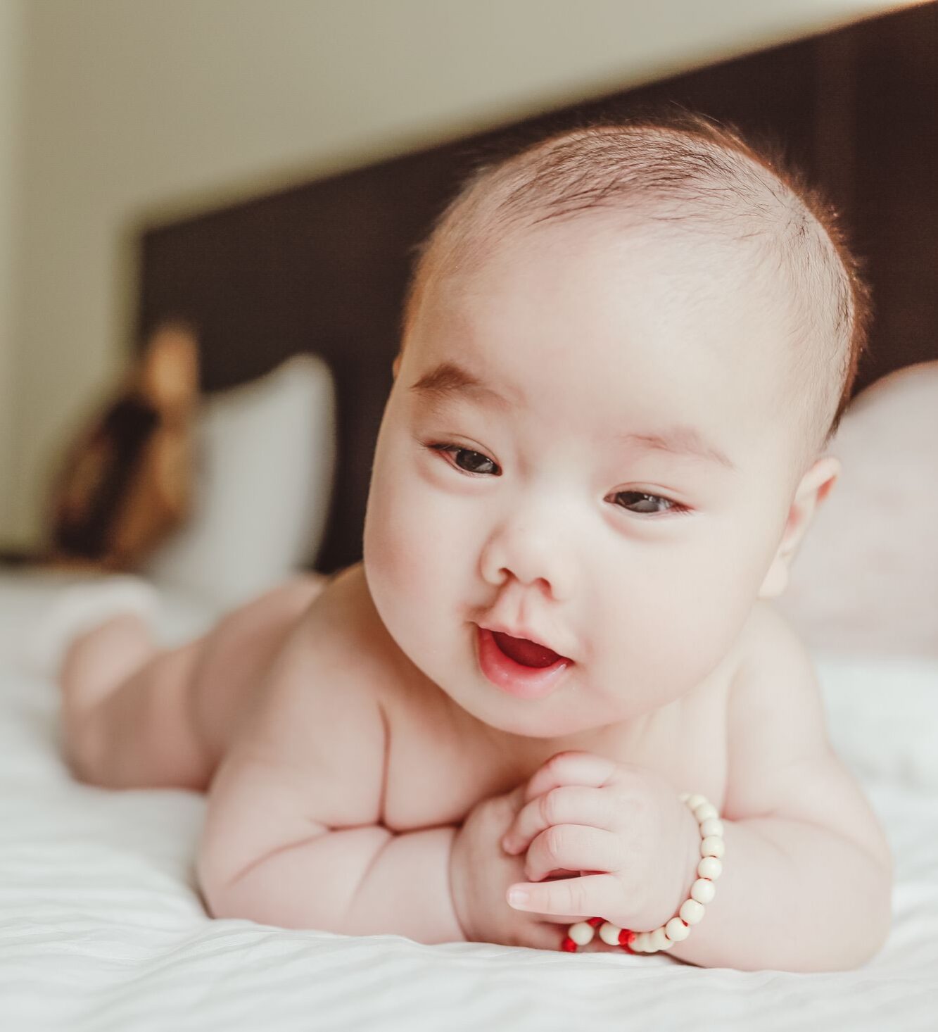 Happy baby lying on a bed at home